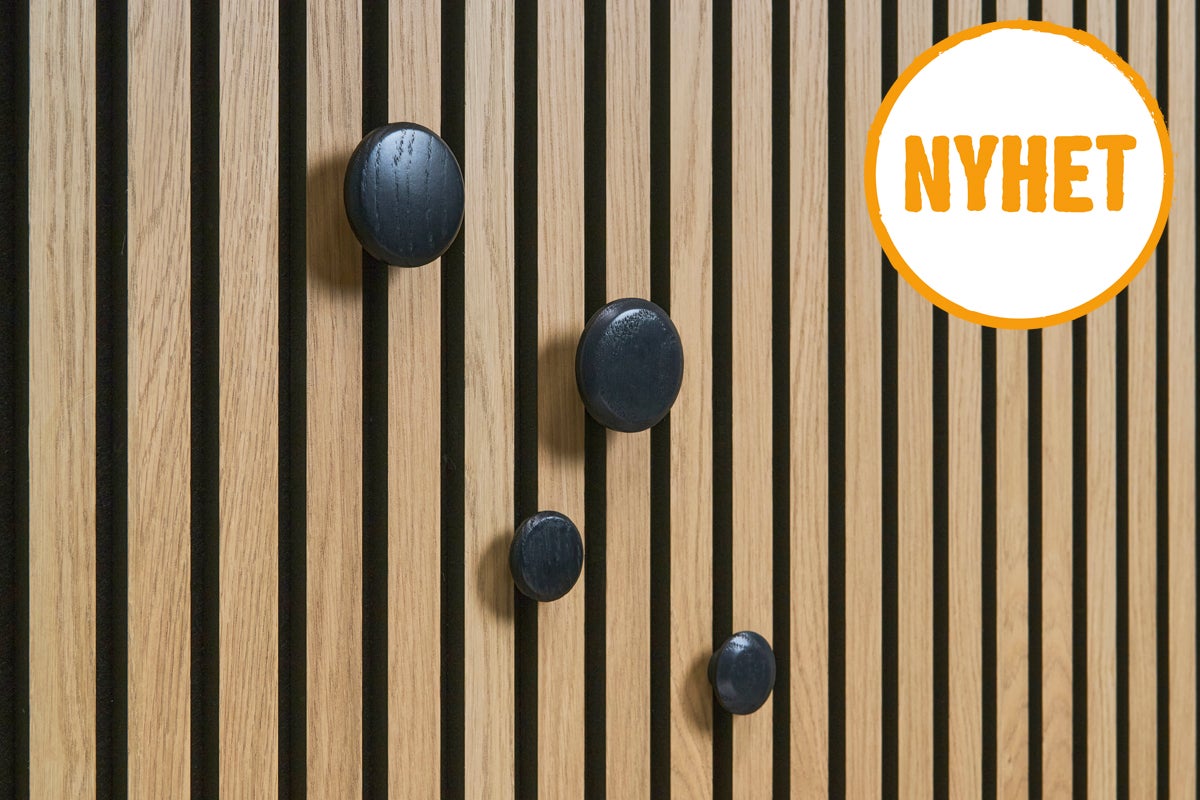 Träpanel med fyra svarta knoppar och texten 'Nyhet'.