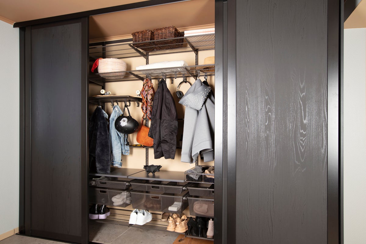 Öppen garderob med skjutdörrar och kläder, skor och accessoarer