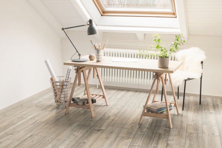 Arbetsrum på vinden med skrivbord, lampa, växt, stol och trägolv