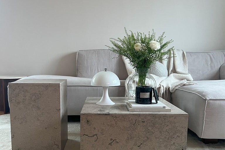Vardagsrum med soffa, bordslampa, blomvas och sidobord