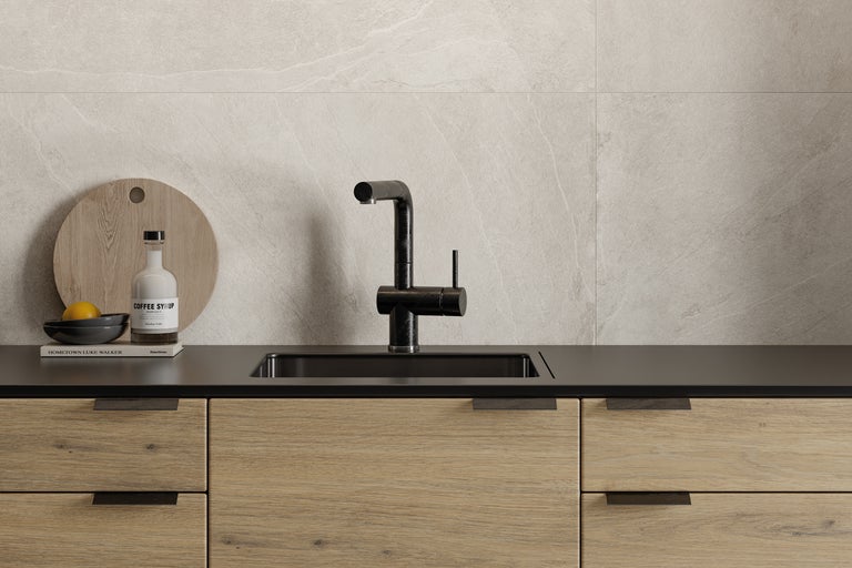 Köksscen med diskho, armatur och träelement mot en kaklad bakgrund