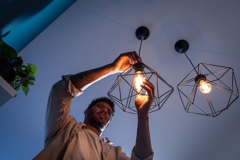En man byter en glödlampa i en geometrisk taklampa