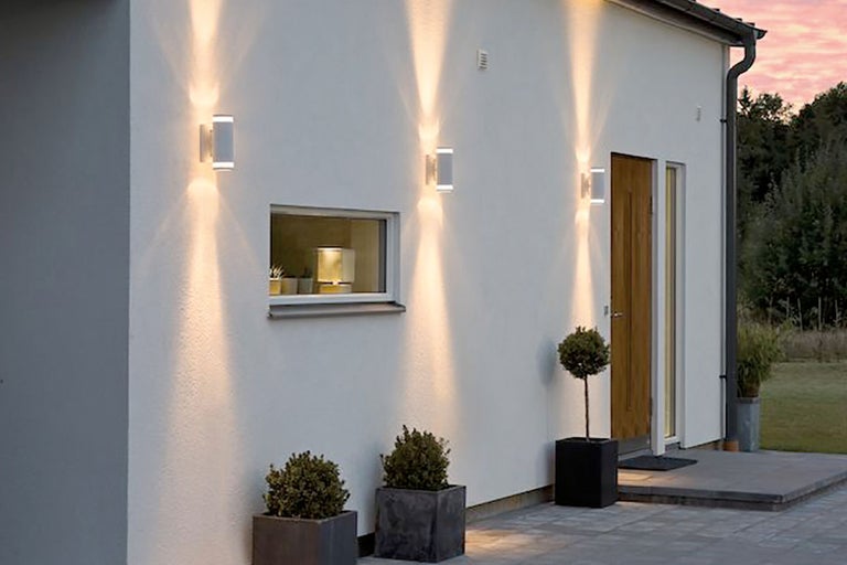 Husfasad med vägglampor för utomhusbruk, fönster och blomlådor