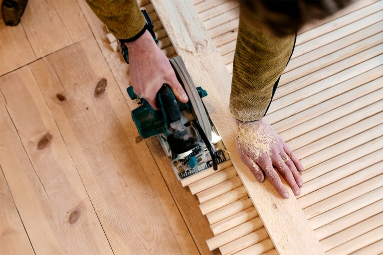Hantverkare sågar träribbor med en cirkelsåg på ett trägolv