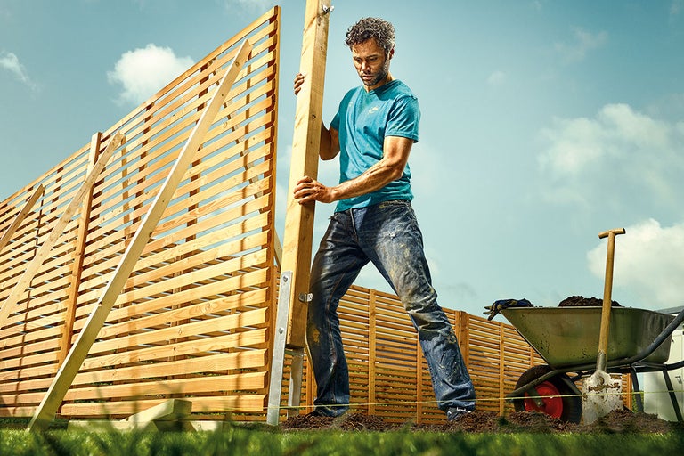 Man bygger ett trästaket i trädgården.