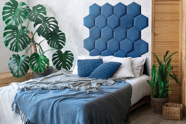 Sovrum med blå hexagonformad väggpanel som sänggavel och krukväxter.