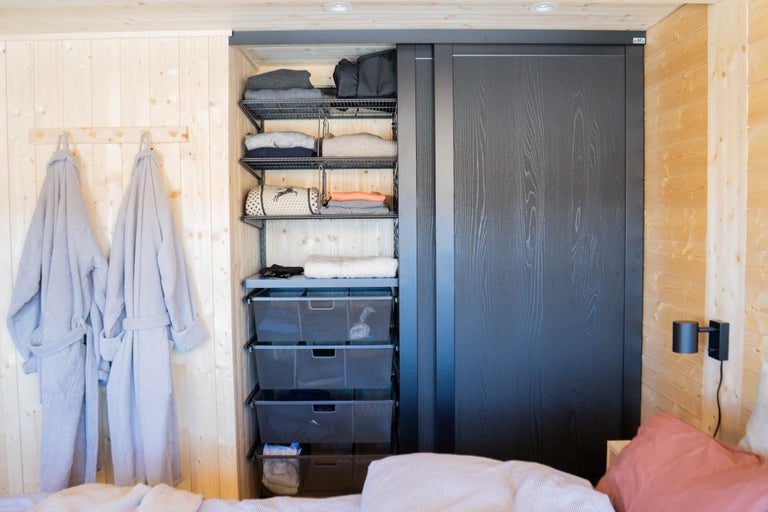 Sovrum med träpanel, skjutdörrsgarderob, hyllor och badrockar