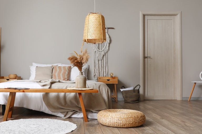 Ljust sovrum med säng, träbord, rottinglampa och dekorationer