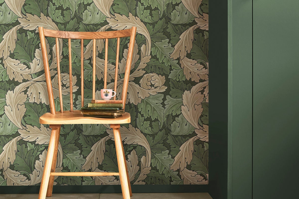 Scen med en trästol framför en vägg med tapet med bladmönster.