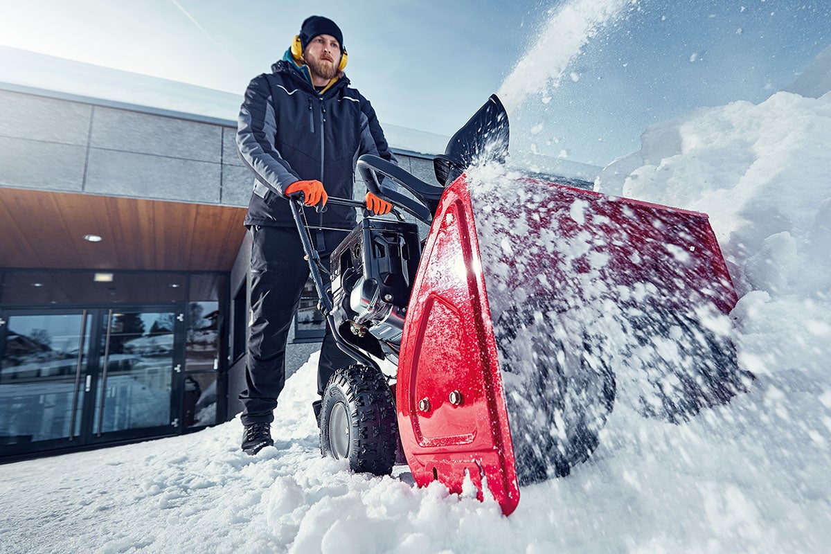 En person använder en snöslunga för att röja snö.