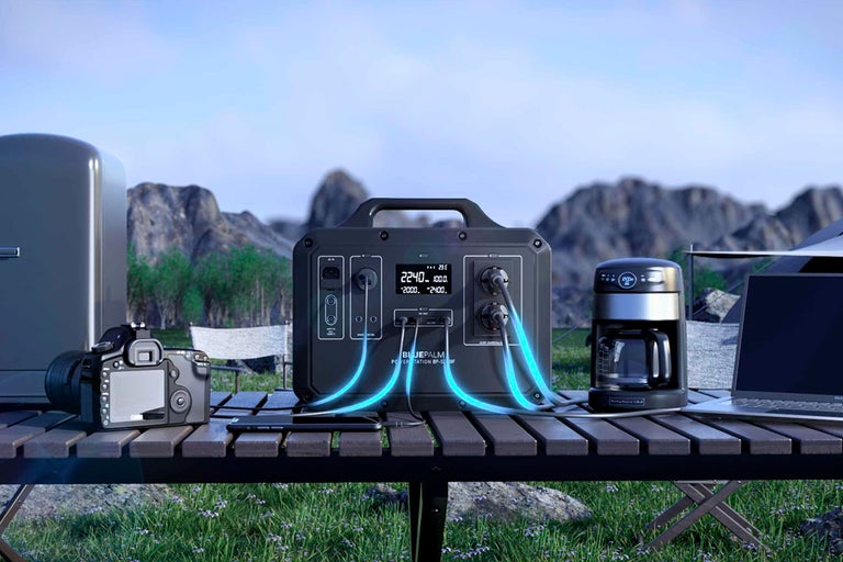 Scen med en bärbar kraftstation ansluten till kamera, minikylskåp, kaffebryggare och laptop utomhus
