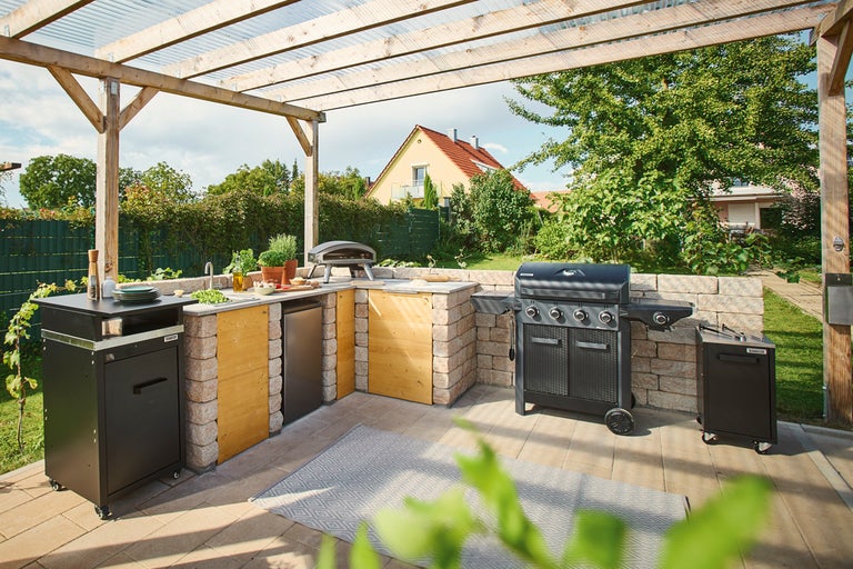 Utomhuskök med grill, diskho och pizzaugn på en terrass