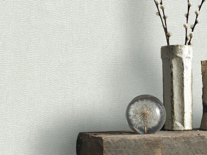 Tapet med fin struktur bredvid dekorativa element som en maskros och en vas med kvistar