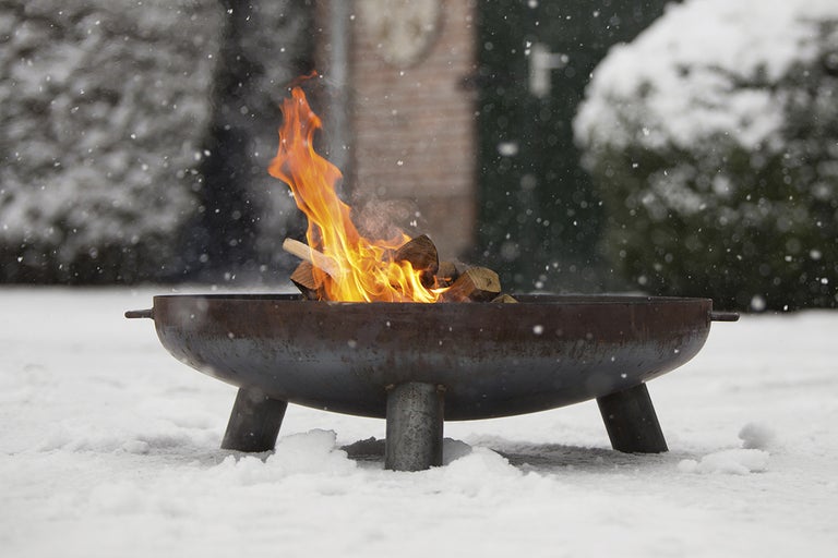 Eldstad med ved på snö