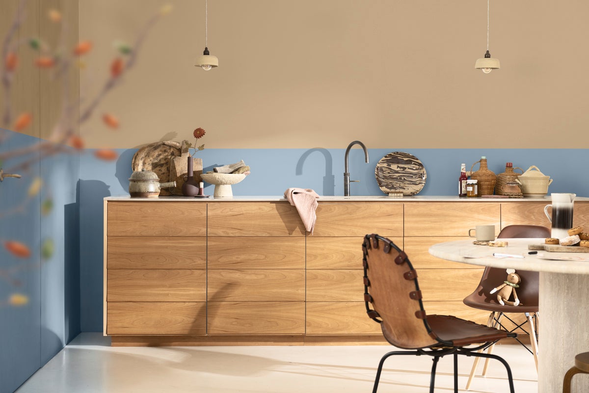 Ljust kök med träskåp, matbord och stolar under hängande lampor