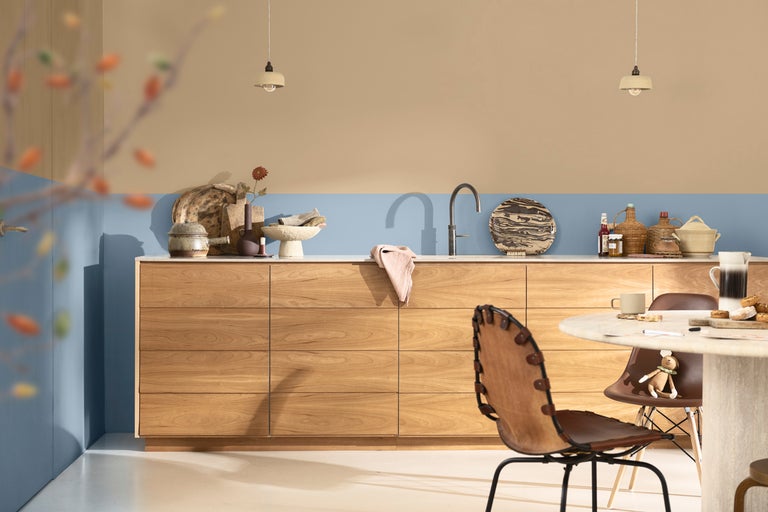 Ljust kök med träskåp, matbord och stolar under hängande lampor