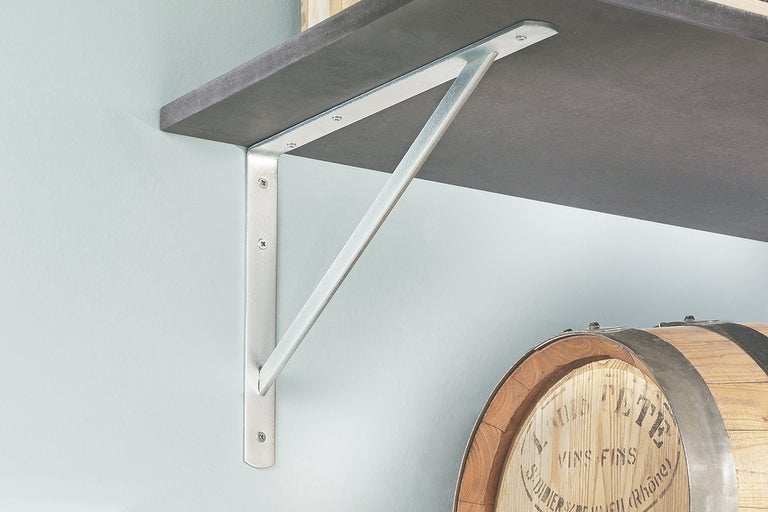 Hylla med silverfärgade fällbara hyllkonsoler och en mörk hyllplan