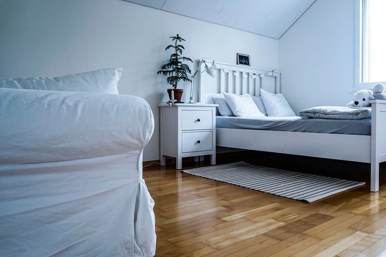 Ljust inrett sovrum med säng, sängbord och soffa