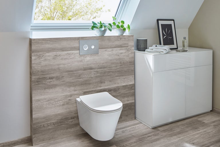 Badrum med vägghängd toalett, manöverpanel, tvättställsskåp och takfönster