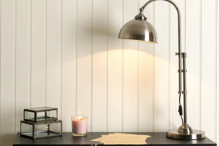 Bordsscen med skrivbordslampa, ljus och dekorativa lådor på ett mörkt bord