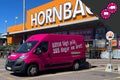 Rosa transportbil med texten Alltid lågt pris 365 dagar om året parkerad framför ett Hornbach byggvaruhus.
