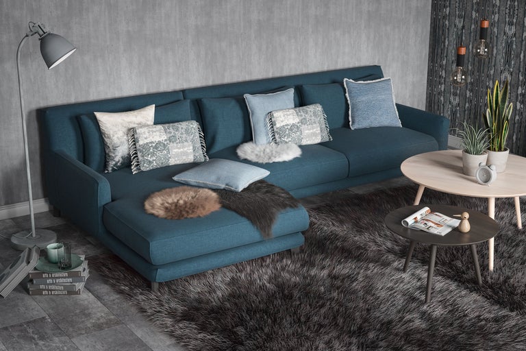 Vardagsrum med blå soffa, kuddar, matta och bord