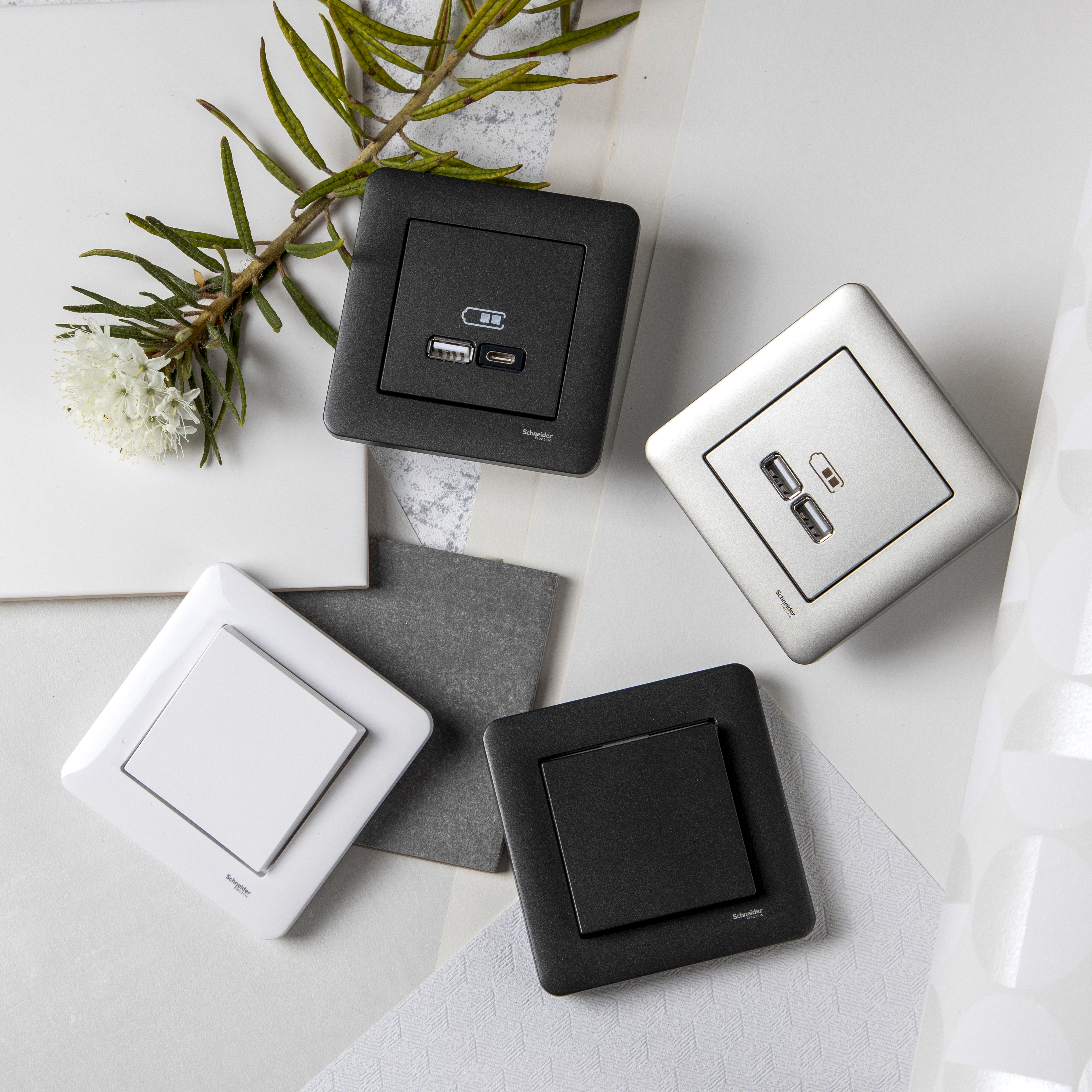 Närbild av olika Schneider Electric uttag och strömbrytare med USB-port, samt bladverk