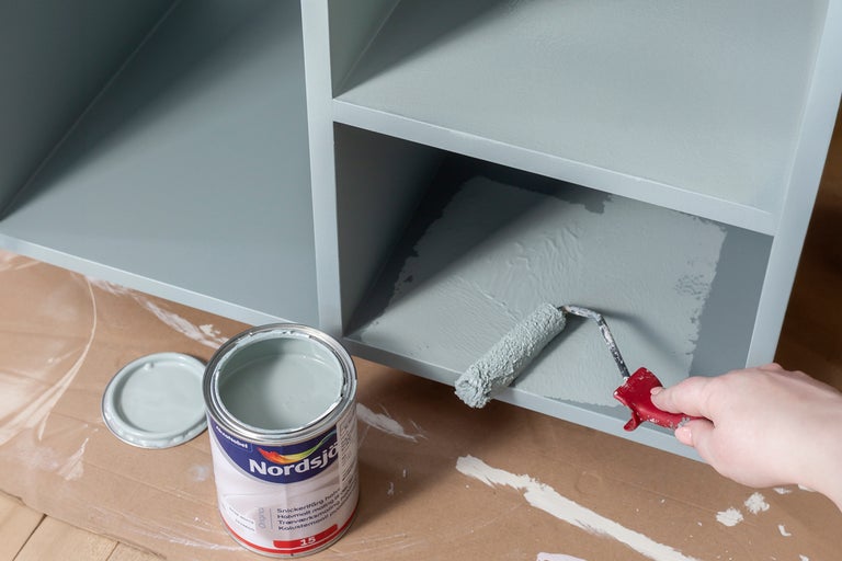 Hylla målas med färgroller och färg