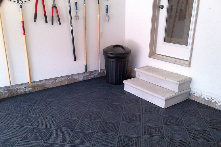 Garage med golvplattor, soptunna, trädgårdsredskap och trappor
