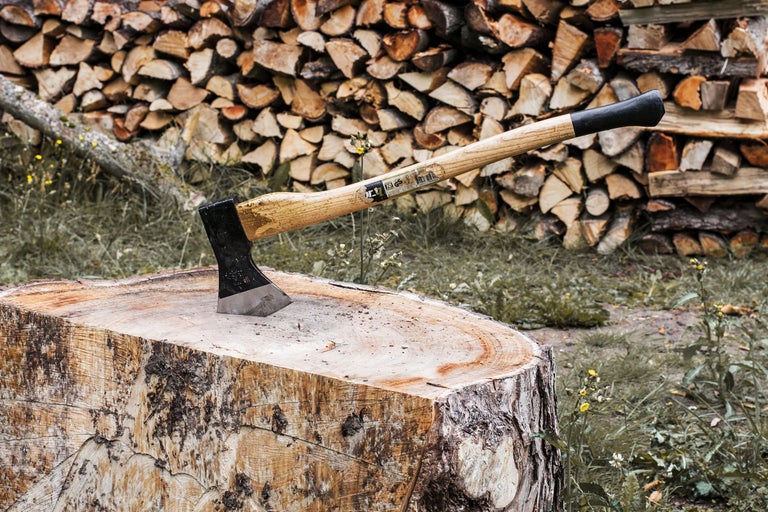 Klyvyxa i trästam framför vedstapel