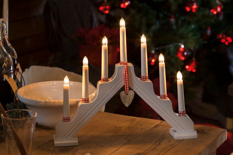 Adventsljusstake med sju ljus på ett träbord framför en julgran