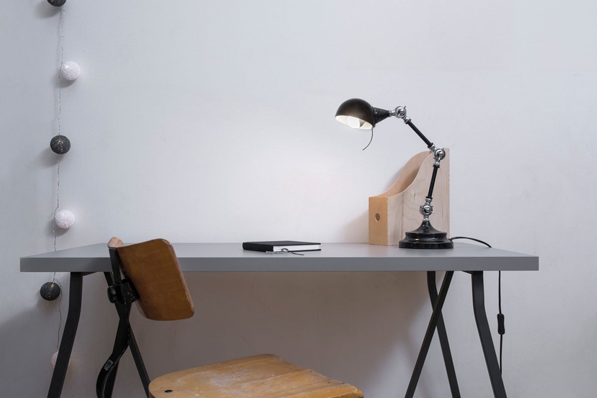 Skrivbord med lampa, anteckningsbok och stol för ett arbetsrum