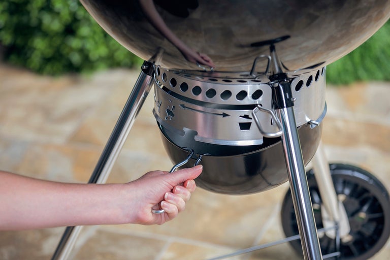 Kolgrill med hand som tömmer askbehållaren