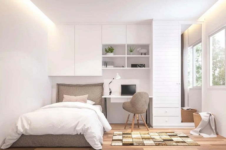 Ljust sovrum med säng, skrivbord och vitt skåp