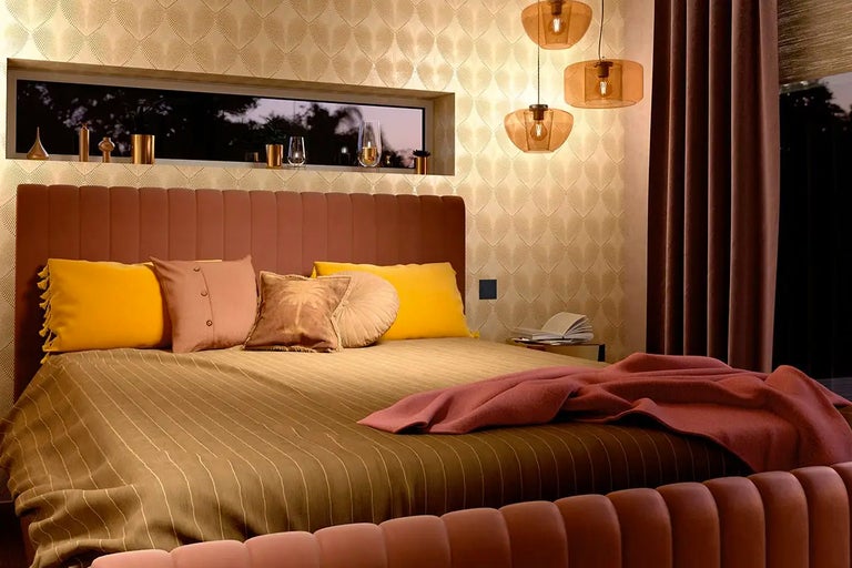 Sovrum med säng, nattduksbord, hänglampor och dekorationer för en stämningsfull atmosfär.