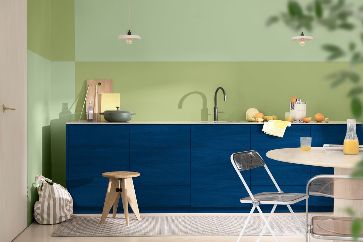 Köksscen med blå skåp, matbord med stolar och köksredskap