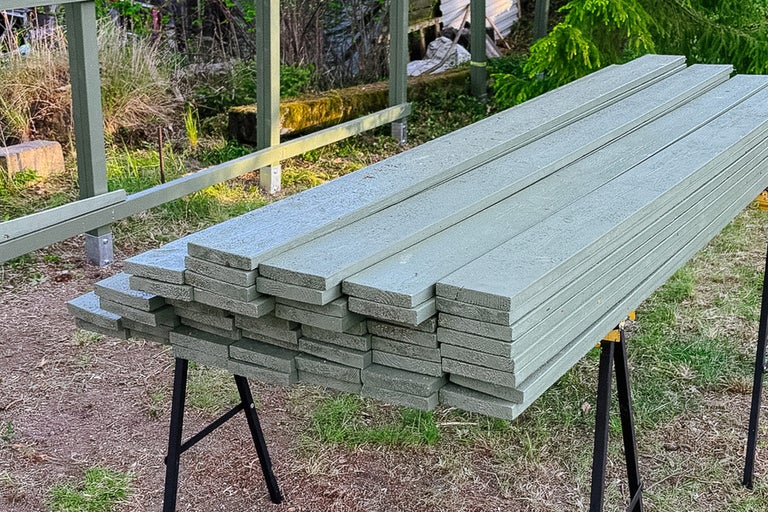 Stapel grå träplankor på ett sågbock
