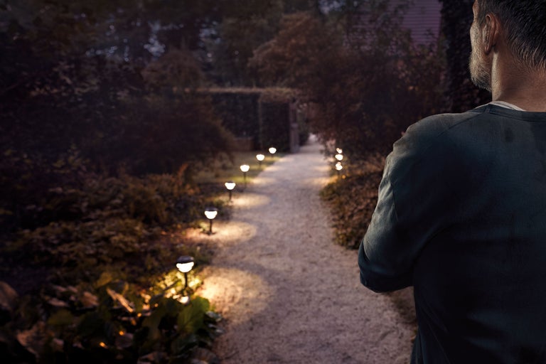 Vägbelysning i trädgården med en man i förgrunden