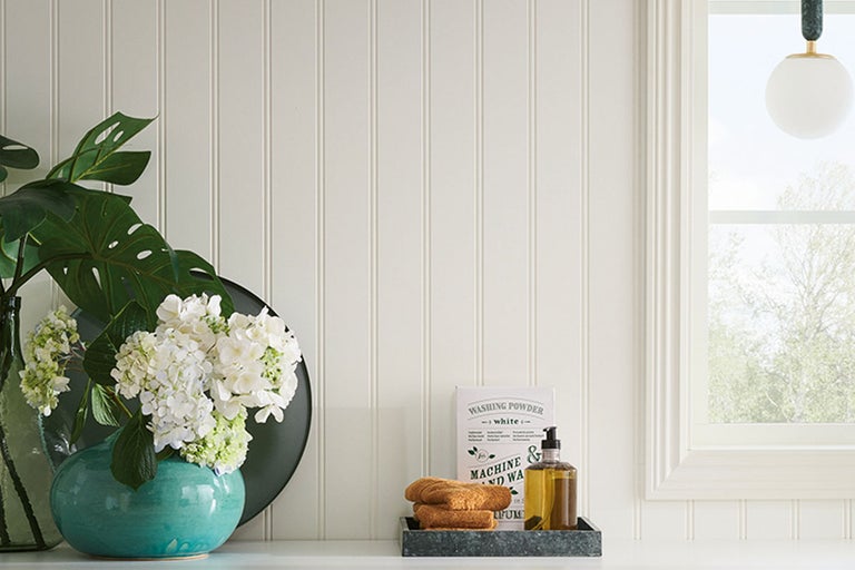 Dekorativt rum med väggpaneler, blommor och tvättartiklar.
