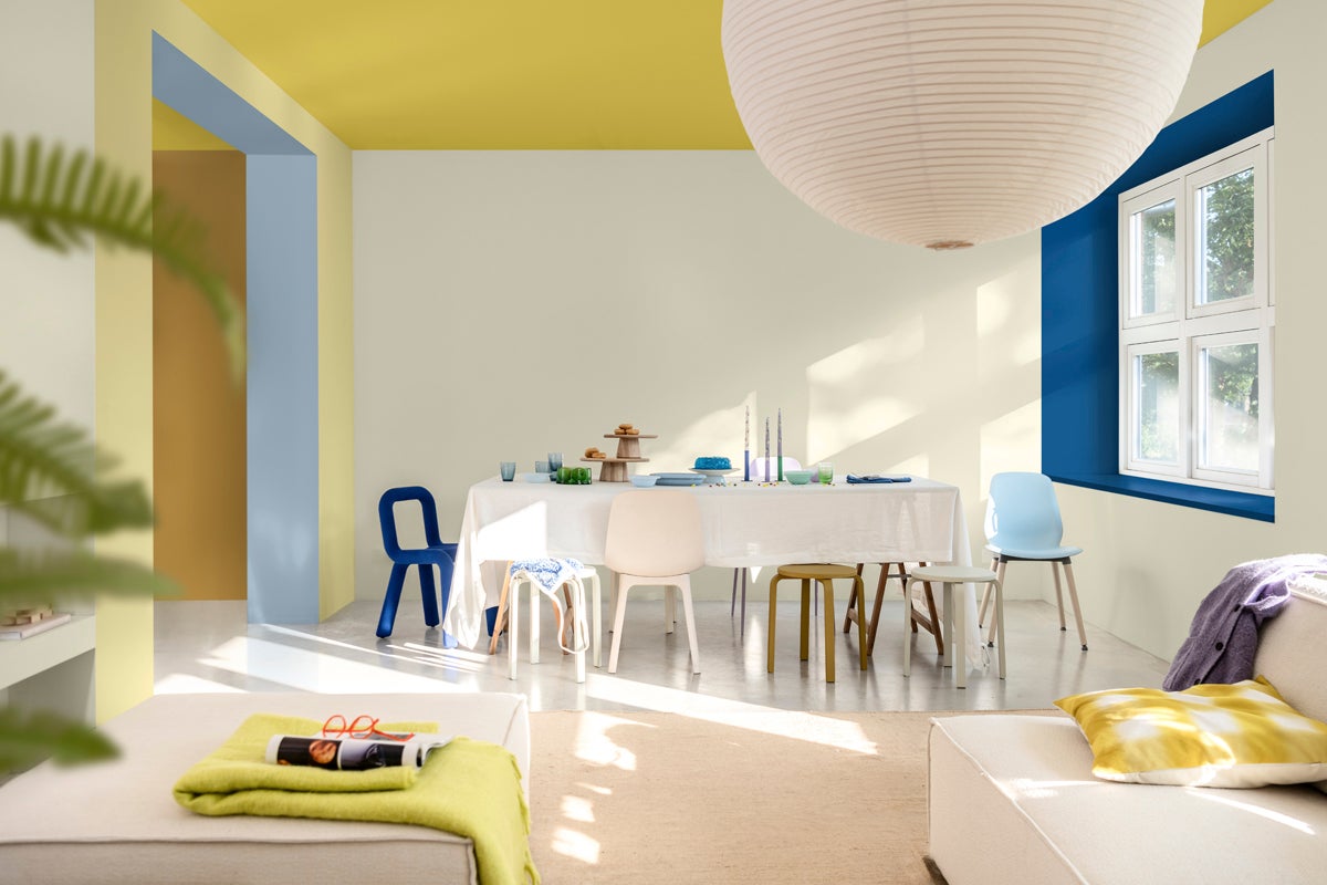 Ljust rum med matbord, stolar och dekorativa element.