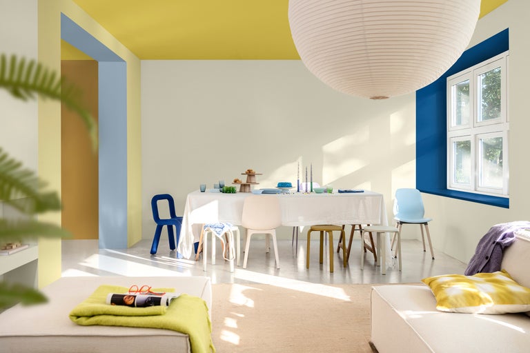 Ljust rum med matbord, stolar och dekorativa element.