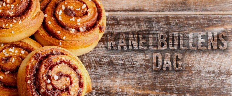 Flera kanelbullar på träunderlag med texten Kanelbullens dag.
