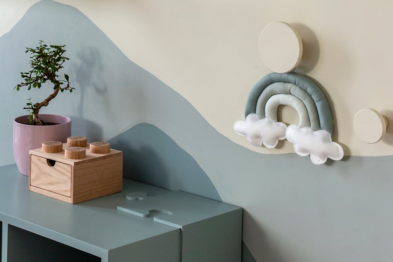 Dekorativt barnrum med träskåp, växt och regnbågs väggdekoration