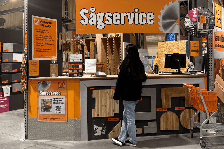 En kund står vid en sågservicebänk i ett Hornbach-byggvaruhus, som ställer ut olika träprover för visning.