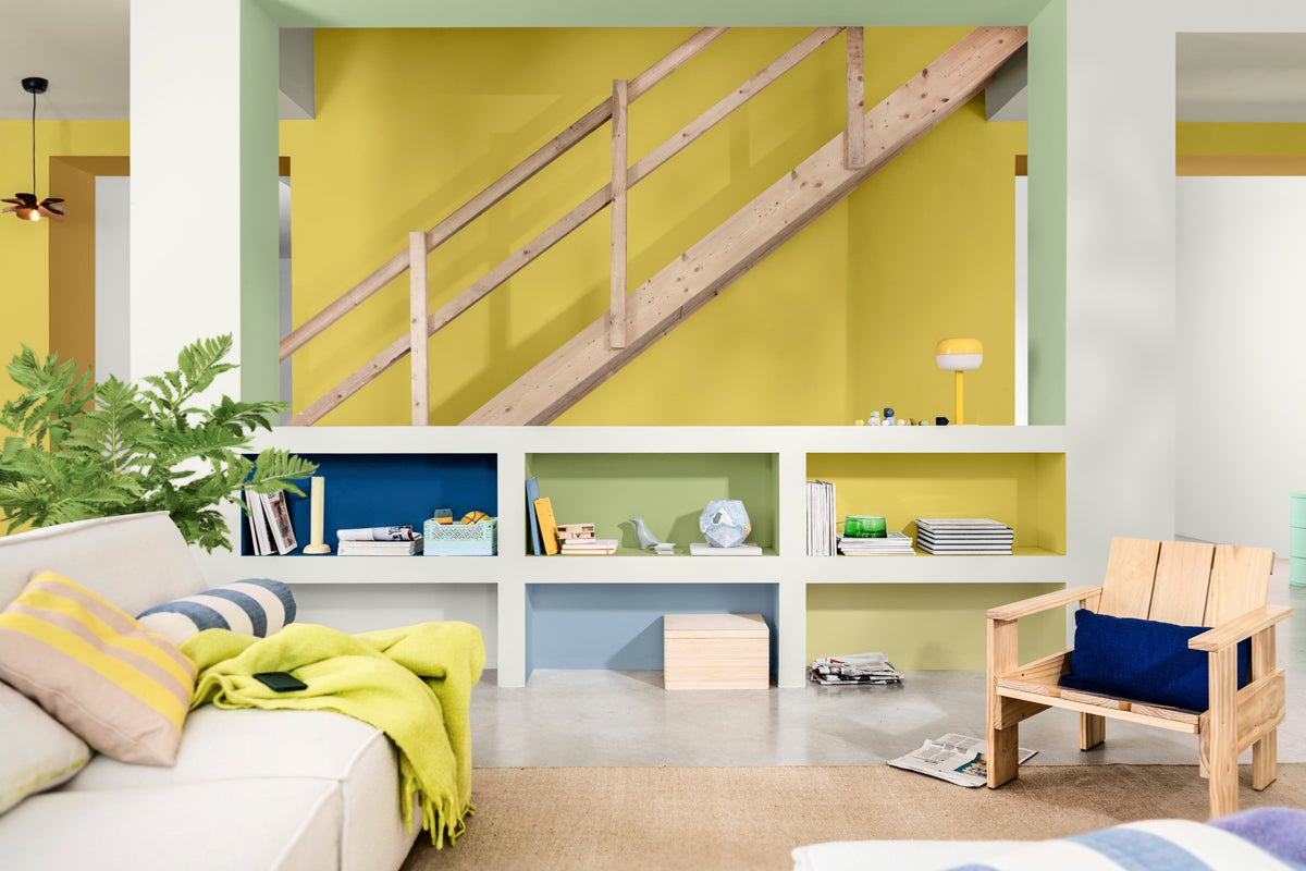 Ljust vardagsrum med trätrappa, hyllvägg och sittplatser