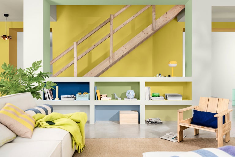 Ljust vardagsrum med trätrappa, hyllvägg och sittplatser