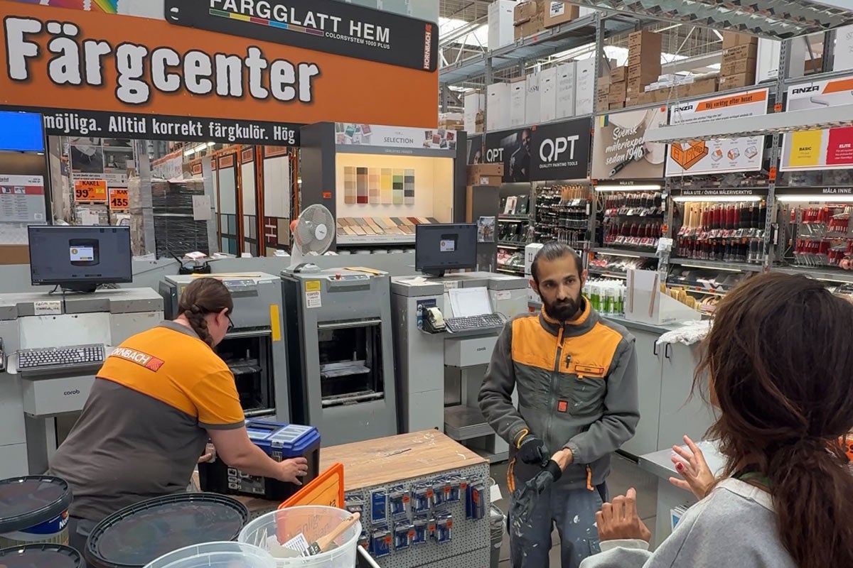 Scen på ett Hornbach färgblandningscenter med personal och färgblandningsmaskiner