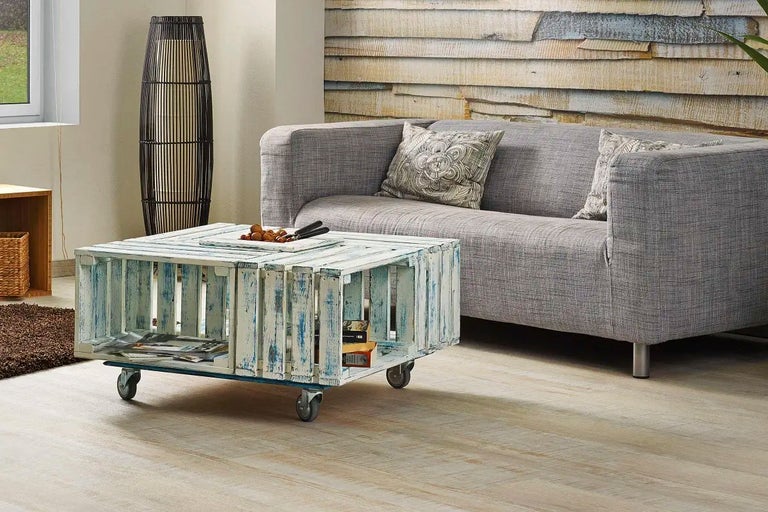 Vardagsrum med soffa, golvlampa och sidobord tillverkat av trälådor på hjul