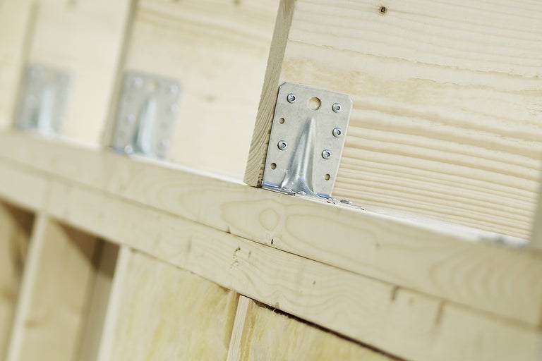 Detaljvy av en träkonstruktion med vinkelbeslag för att sammanfoga träbjälkar.