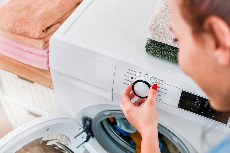 Kvinna ställer in tvättmaskin med textilier